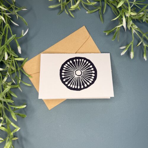 A mini card with a black single wheel design on a green background with a plant