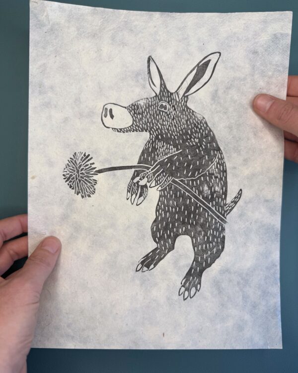 Aardvark Lokta print A black ink print of an Aardvark on natural Lokta paper held over a green background.