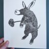 A black ink print of an Aardvark on a white card held over a green background.