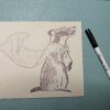A badger image on a piece of linoleum with a Sharpie pen on a green background.