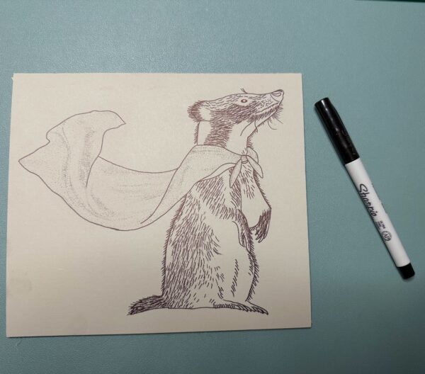 A badger image on a piece of linoleum with a Sharpie pen on a green background.