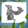 A black ink Badger print on white paper on a green background with a plant