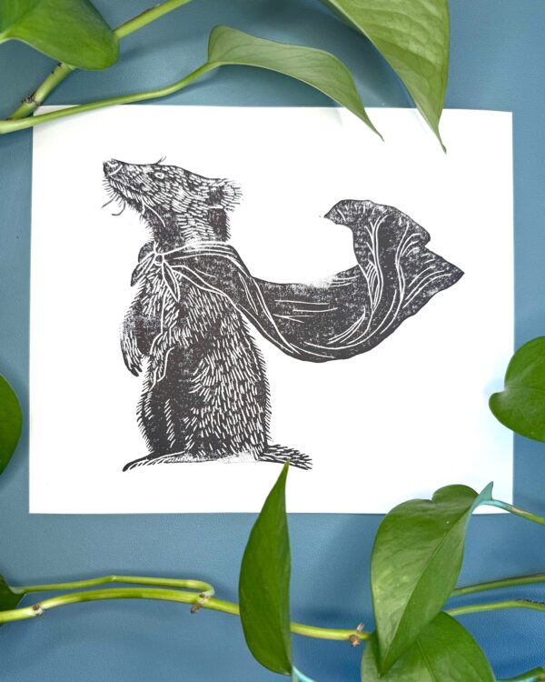 A black ink Badger print on white paper on a green background with a plant