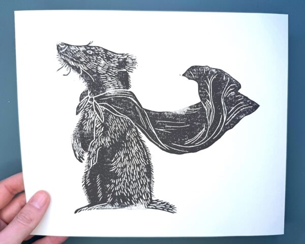 A badger print on white paper held by a hand over a green background